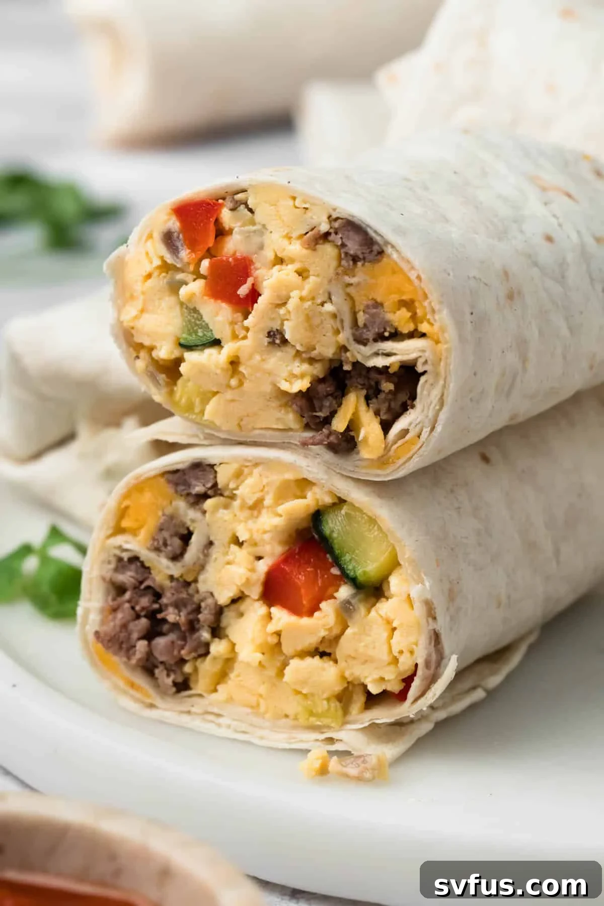 side view of a halved breakfast burrito on a plate.
