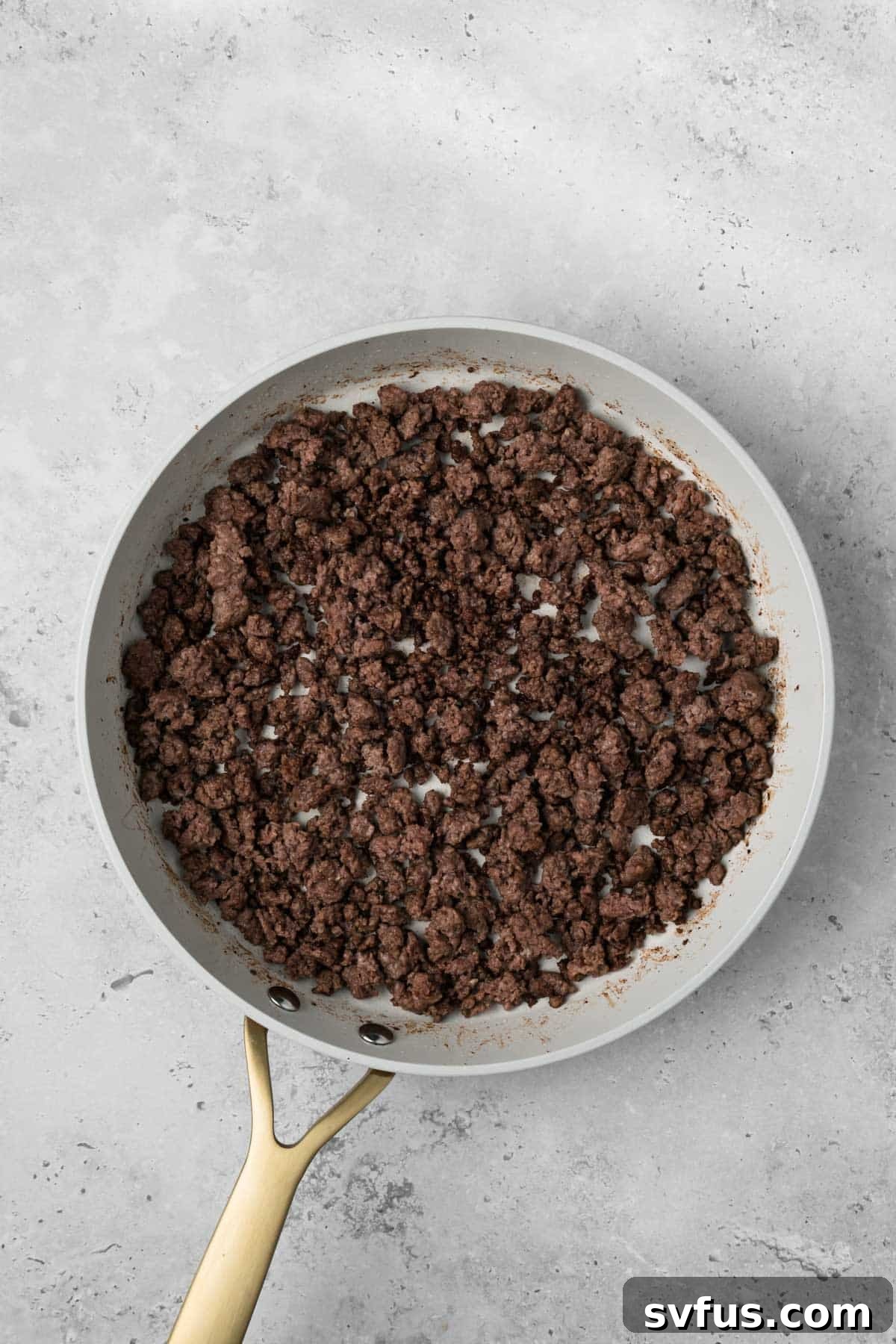 overhead view of cooked ground meat for breakfast burritos in a skillet.