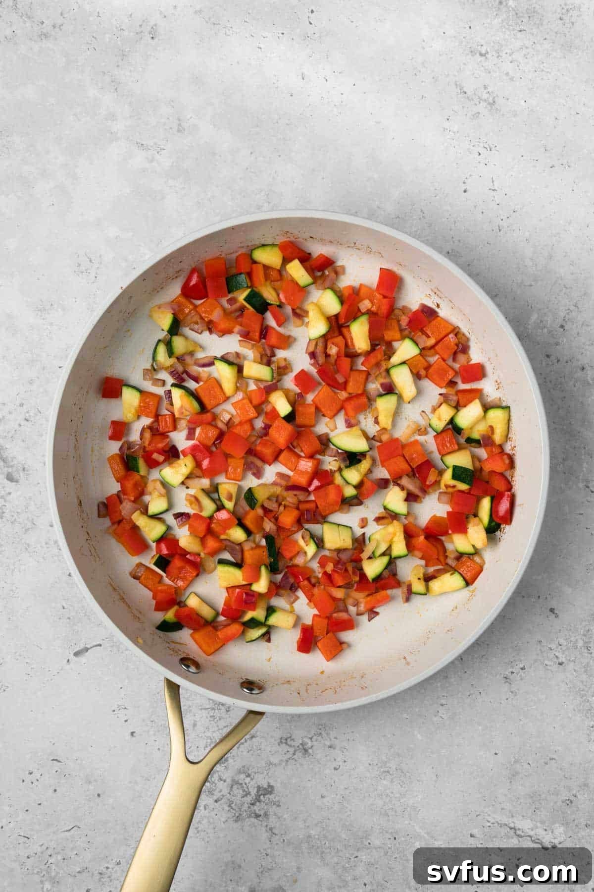 overhead view of cooked vegetables for breakfast burritos in a skillet.