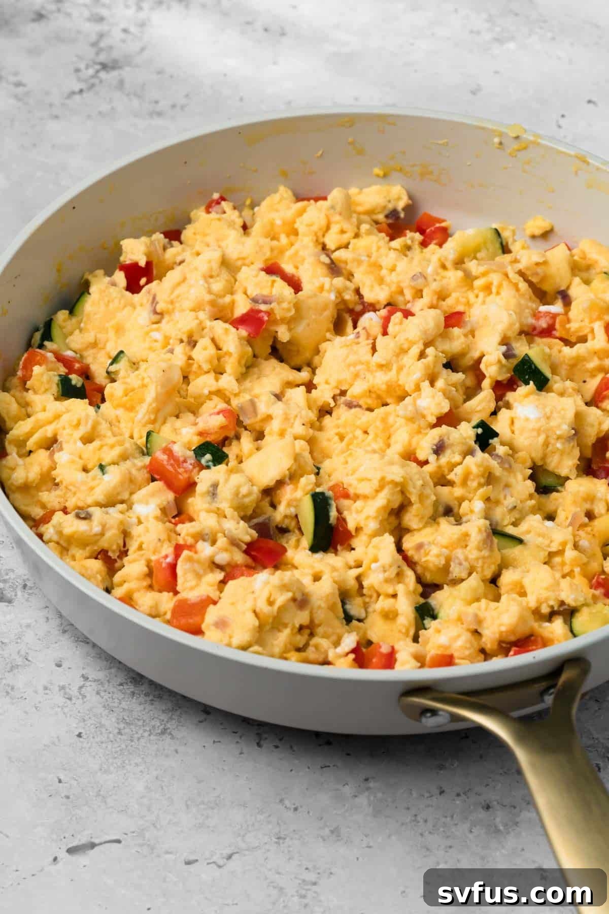 side view of a veggie egg scramble for breakfast burritos in a skillet.