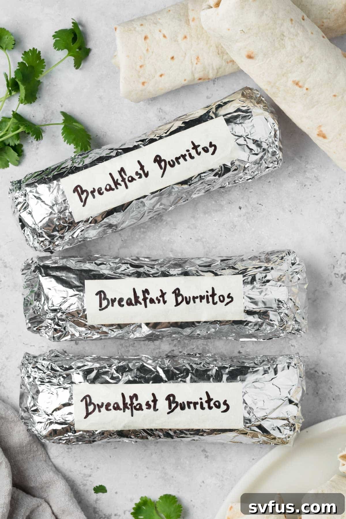 overhead view of labeled breakfast burritos wrapped in foil.