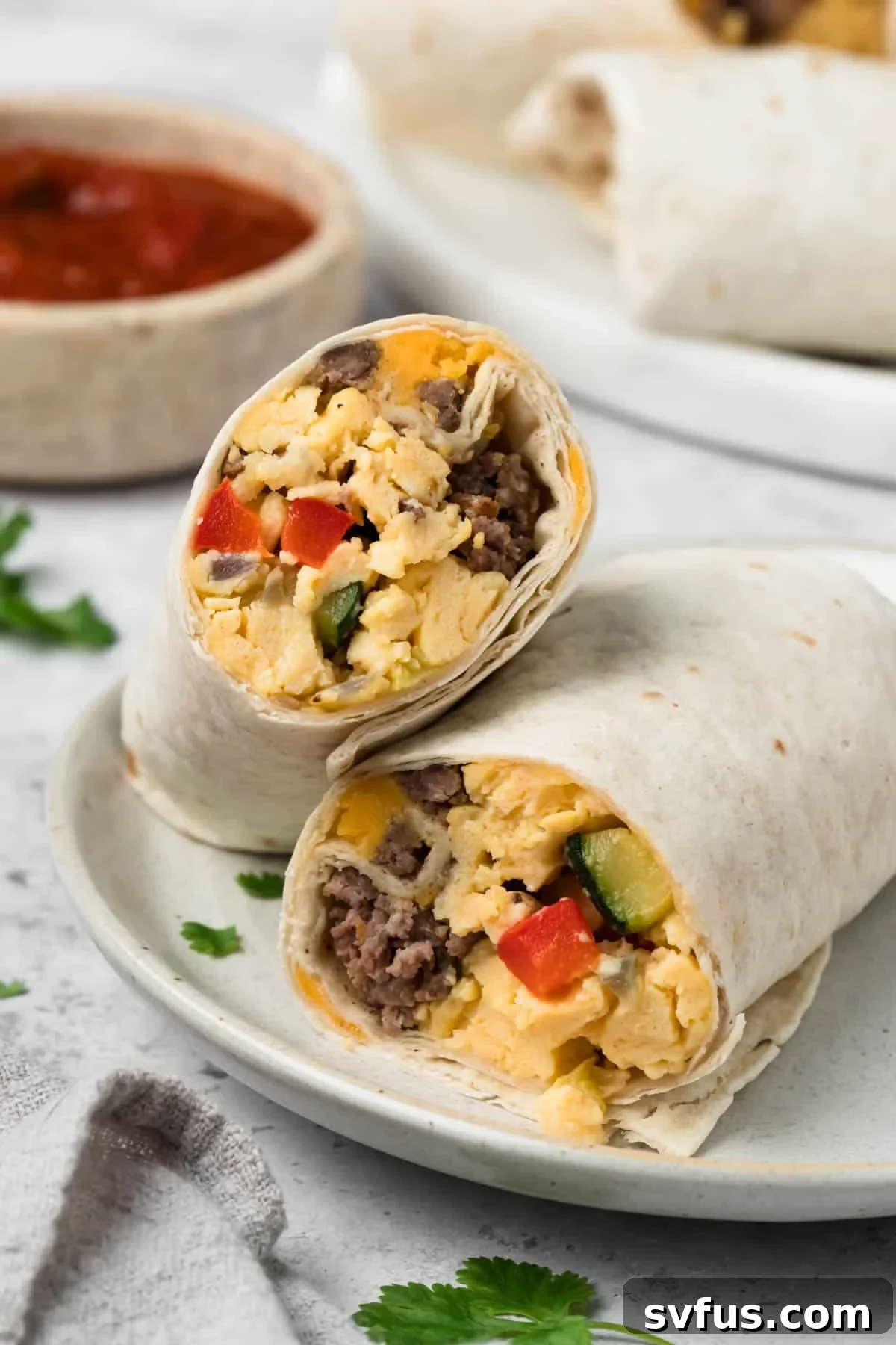 side view of a halved breakfast burrito on a plate.
