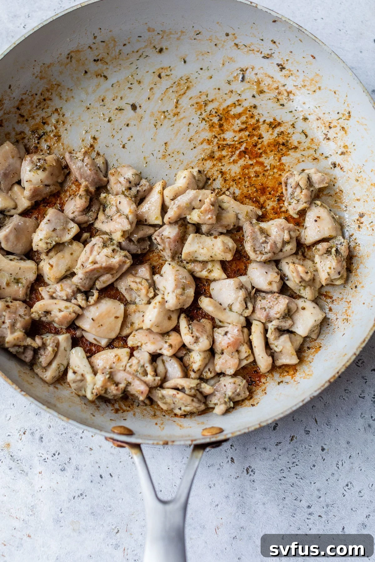 overhead view of cooked chicken thigh pieces in a skillet.