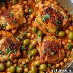overhead view of Moroccan chicken thighs in a chickpea and olive sauce in a large pan.