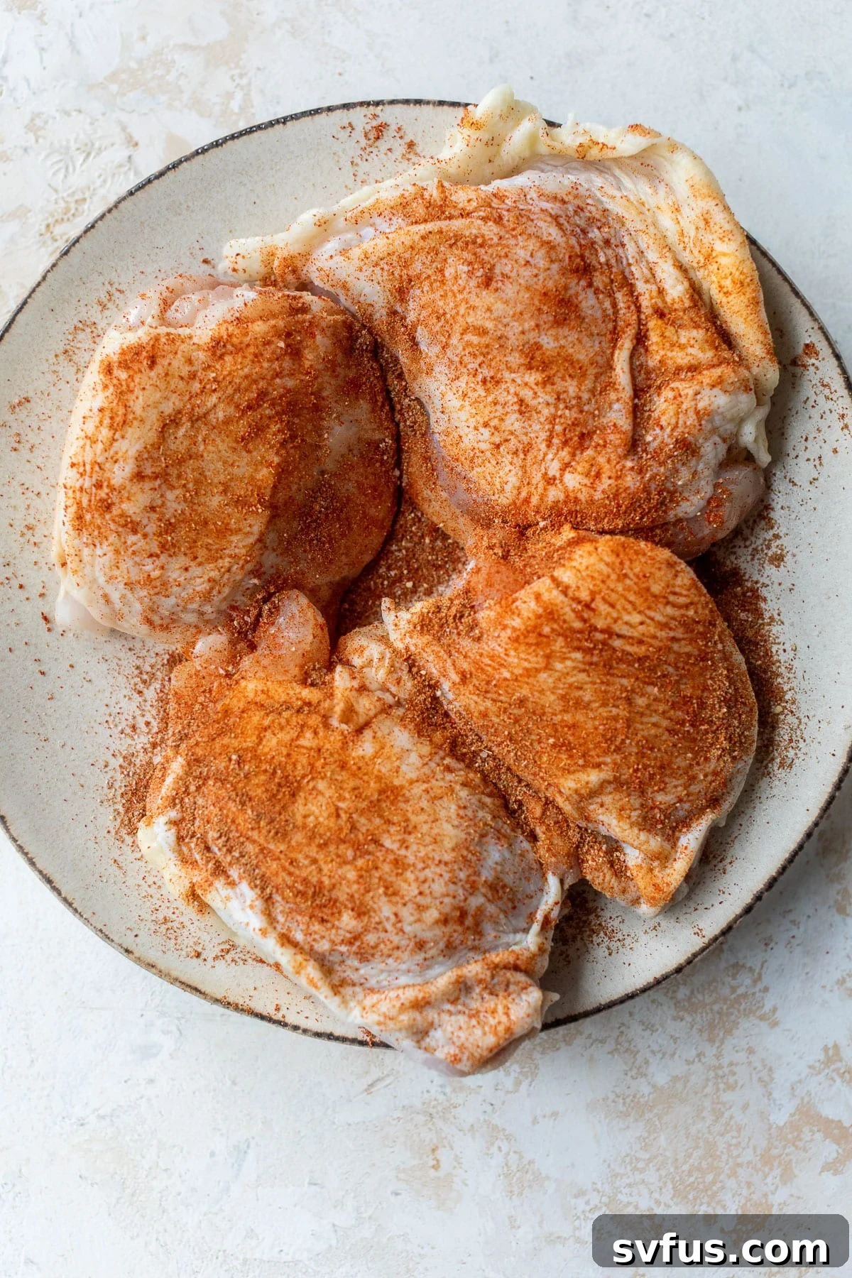 overhead view of seasoned chicken thighs on a plate.