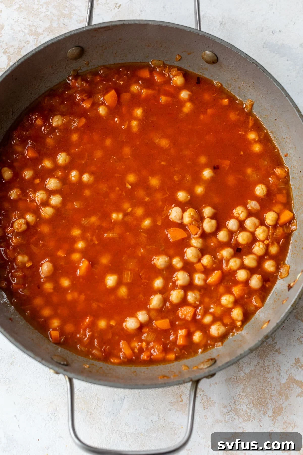 overhead view of a red chickpea sauce simmering in a skillet.